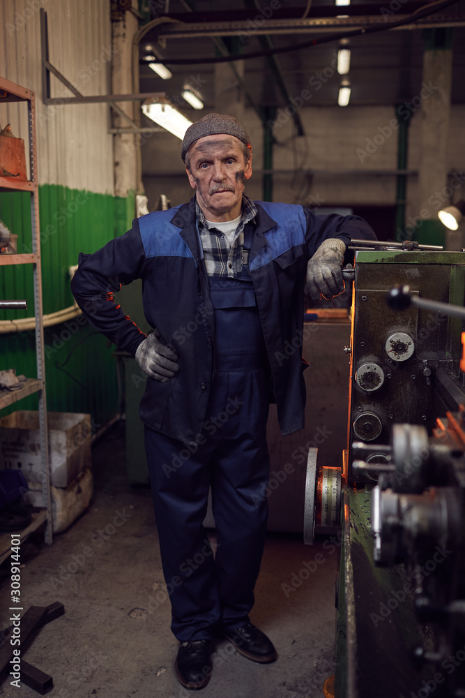 Portrait of manual worker standing in work uniform and looking at camera in the factory