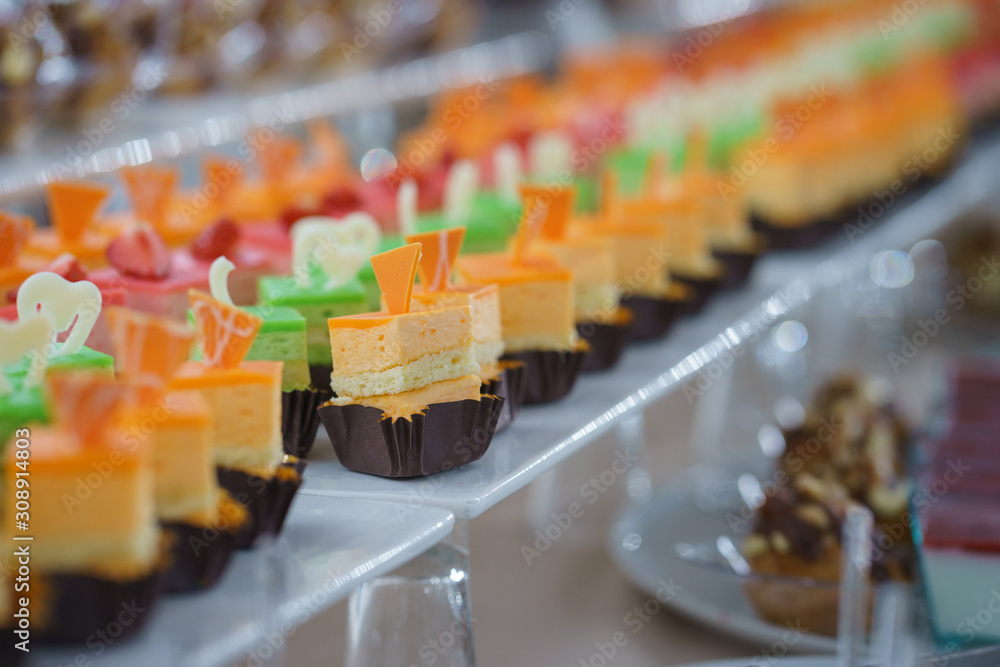 Sweet little desserts cakes in different colors on a plate prepared for the guests of the event. Sweet little desserts cakes in different colors on a plate prepared for the guests of the event.