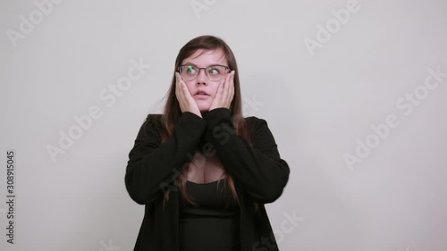 Surprised cheerful young woman in casual black dress, opened mouth, spreading hands isolated on gray background in studio. People sincere emotions, lifestyle concept. photo