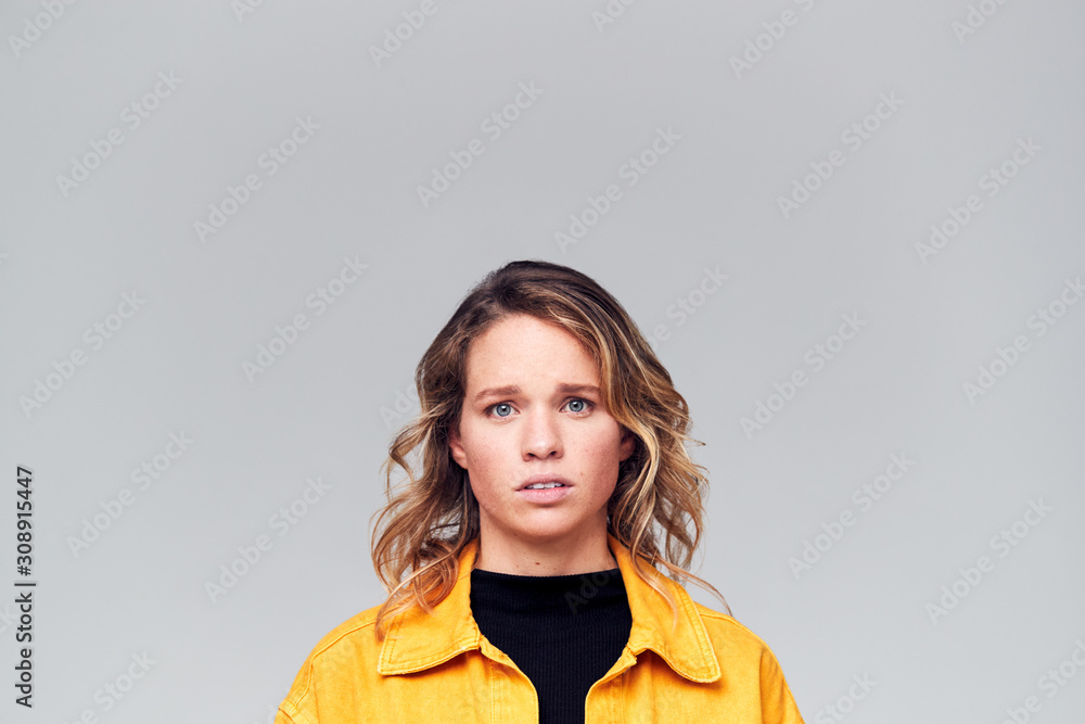 Studio Portrait Of Worried Young Woman Looking At Camera