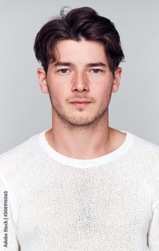 Fototapeta premium Studio Portrait Of Young Man With Serious Expression Looking At Camera