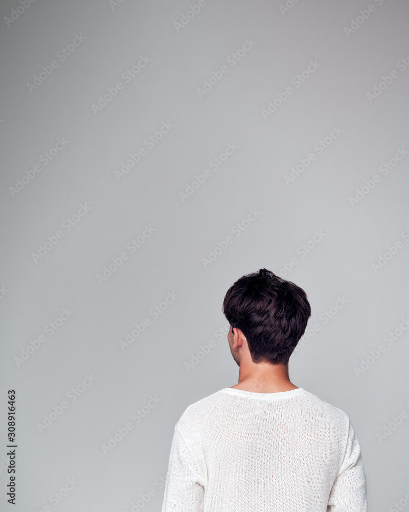 Rear View Of Young Man Looking Away From Camera In Studio Rear View Of Young Man Looking Away From Camera In Studio