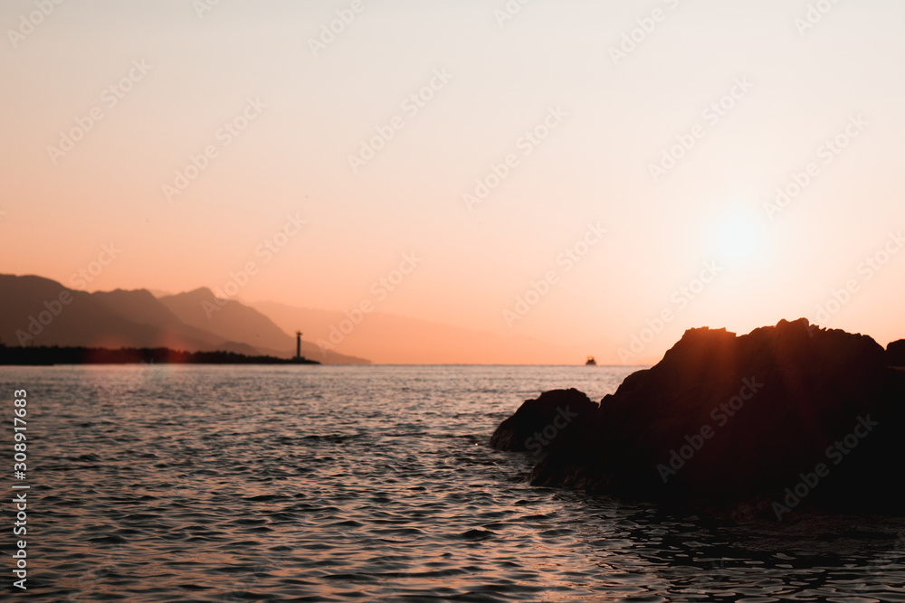 Bright sun early morning sunrise on a rocky beach in split, croatia