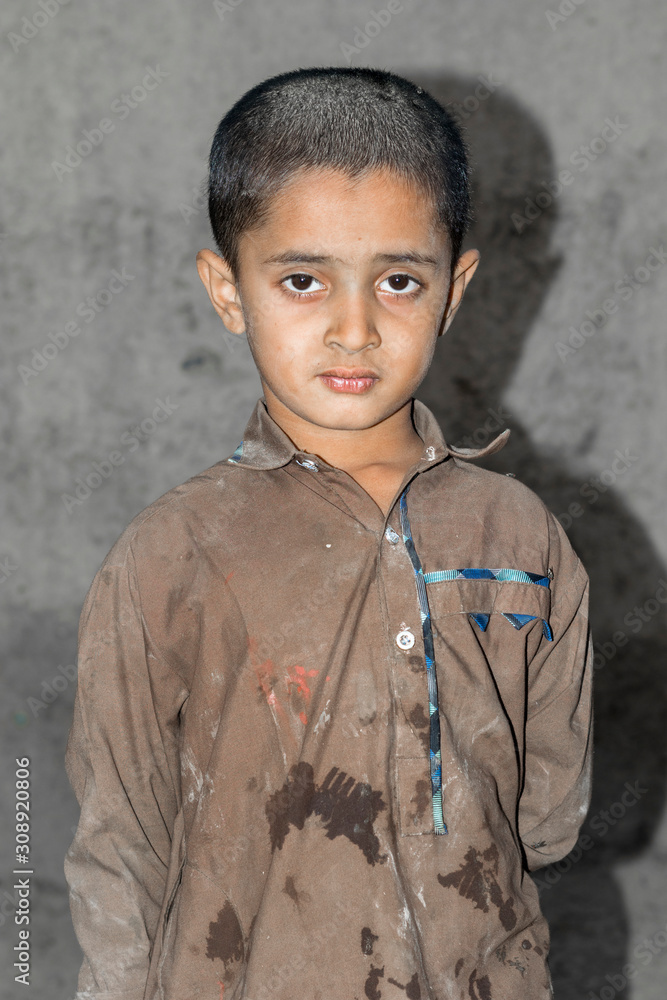 Φωτογραφία closeup of a poor staring hungry orphan boy in a refugee camp with sad expressio