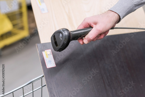 Man with manual scanner of barcodes scans and buying plywood, mdf lying in a shopping cart in a hardware store. self catering