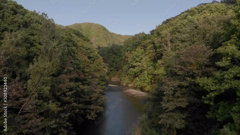 Aerial shot slowly rising above dense green forest and river in Jozankei famous onsen hot spring town Hokkaido, Japan Aerial shot slowly rising above dense green forest and river in Jozankei famous onsen hot spring town Hokkaido, Japan