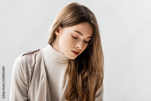 dreamy, stylish woman looking down isolated on grey