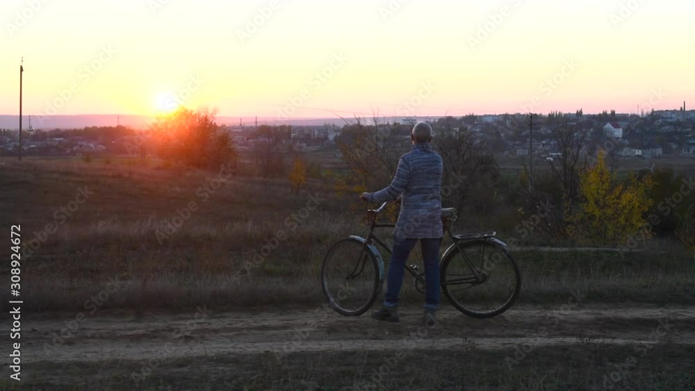 Old man with a gray hair and beard walking with a bicycle along road, rustic style Old man with a gray hair and beard walking with a bicycle along road, rustic style