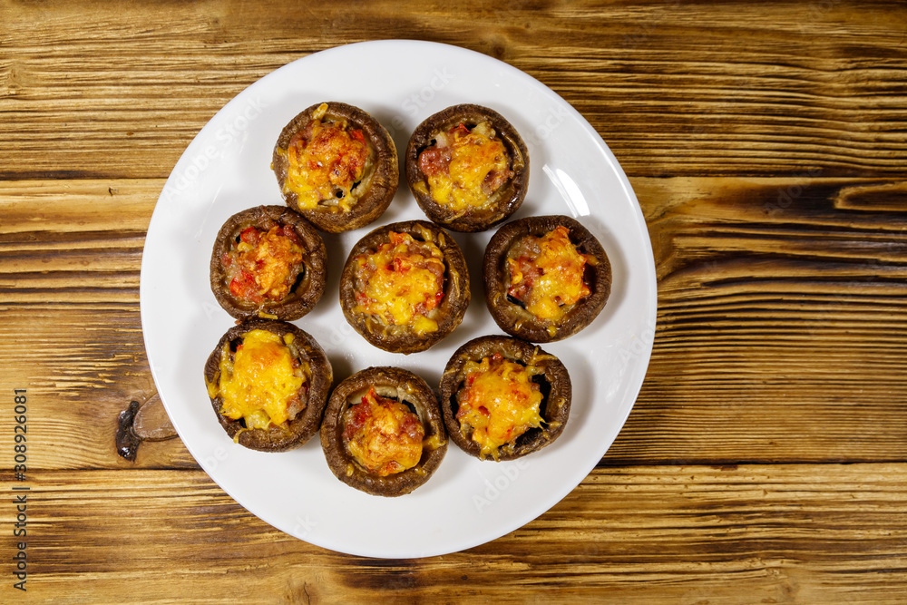 Baked mushrooms stuffed with minced meat, mushroom, paprika, onion and cheese on wooden table. Top view