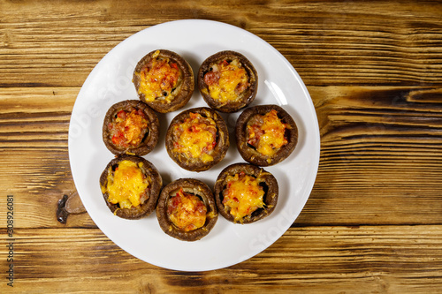 Baked mushrooms stuffed with minced meat, mushroom, paprika, onion and cheese on wooden table. Top view