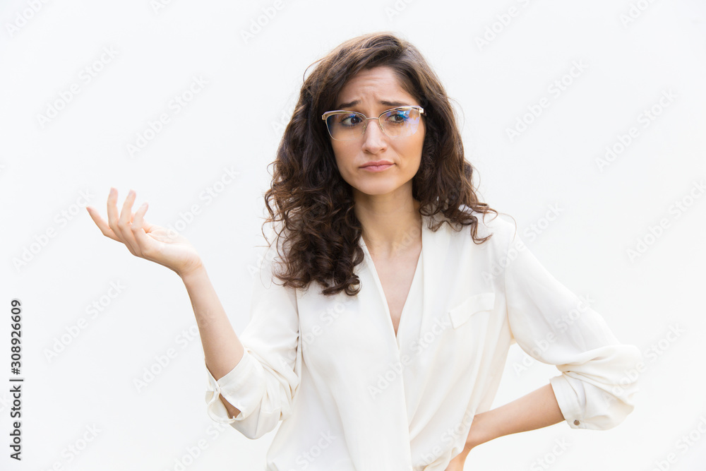 Puzzled clueless woman in glasses shrugging. Wavy haired young woman in casual shirt standing isolated over white background. Shrugging concept Puzzled clueless woman in glasses shrugging. Wavy haired young woman in casual shirt standing isolated over white background. Shrugging concept