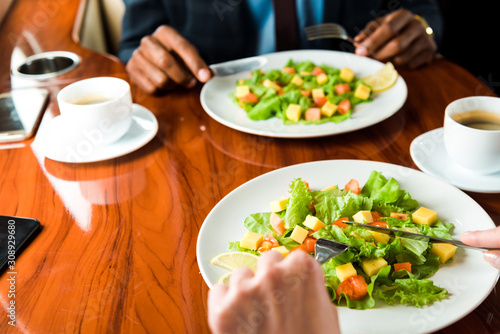 cropped view of african american businessman and businesswoman near tasty dishes in private plane