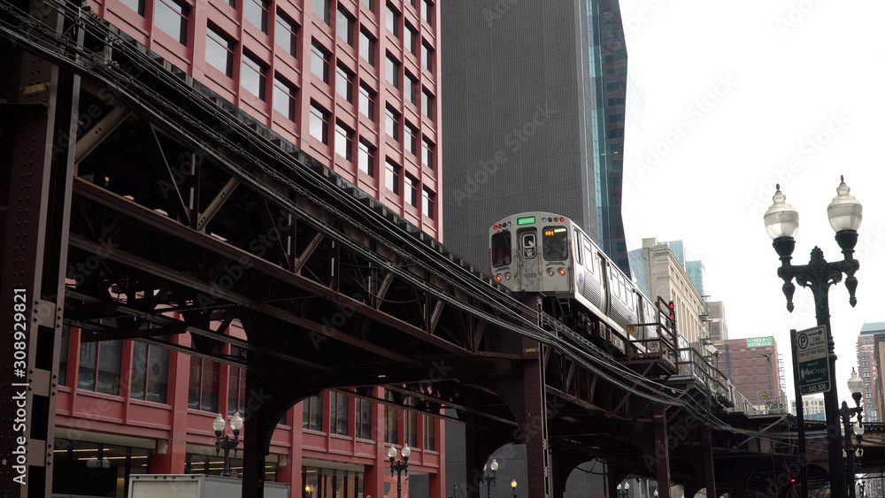 Chicago L train day time exterior establishing shot in front of downtown urban apartment buildings. Luxury expensive real estate location