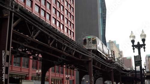 Chicago L train day time exterior establishing shot in front of downtown urban apartment buildings. Luxury expensive real estate location photo