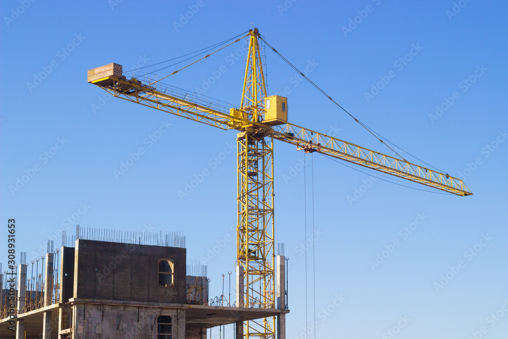 bright yellow construction crane against the blue sky