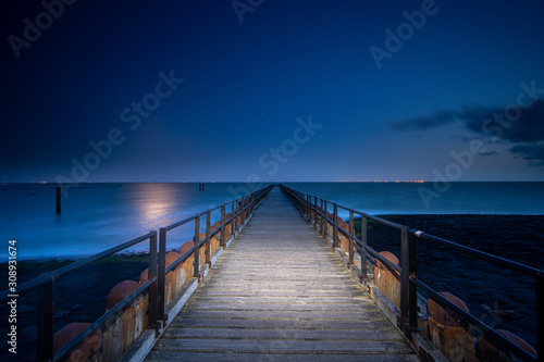 Long wooden pier extends over water toward the horizon. A leading line to the horizone