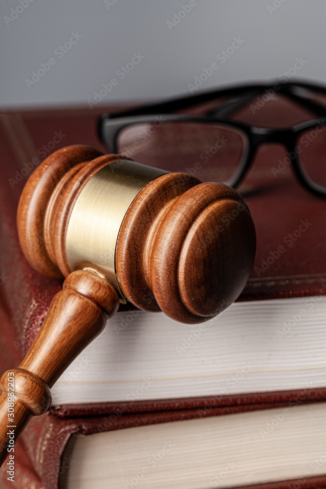 Brown wooden gavel with stack of books on gray table Brown wooden gavel with stack of books on gray table