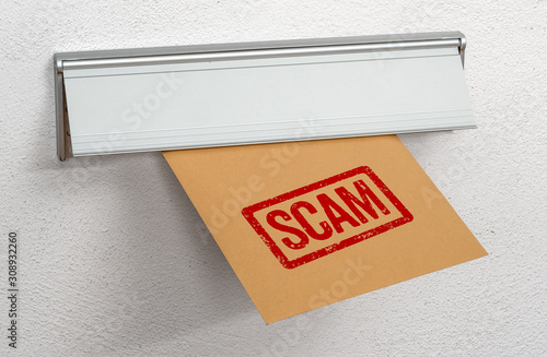 A letter stamped Scam in a mail slot photo