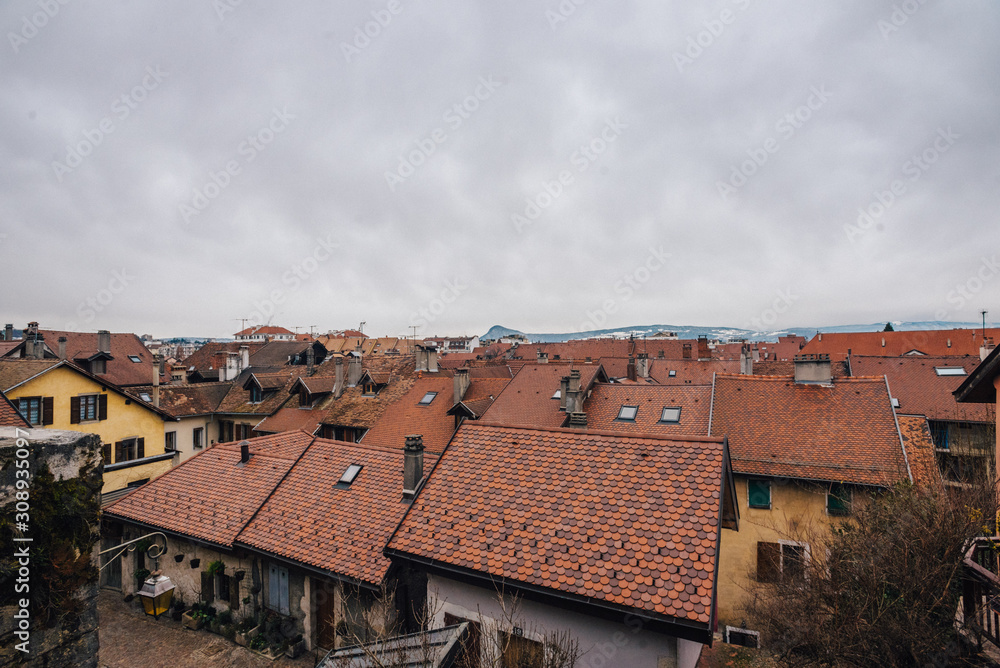 Cityscape of the roofs of European small houses in Annecy, France. Photography of the roofs covered with beautiful red tiles in the Mediterranean city against a cloudy sky.