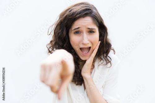 Wallpaper Mural Excited student girl pointing index finger at camera, laughing, mocking. Wavy haired young woman in casual shirt standing isolated over white background. Pointing at you concept Torontodigital.ca