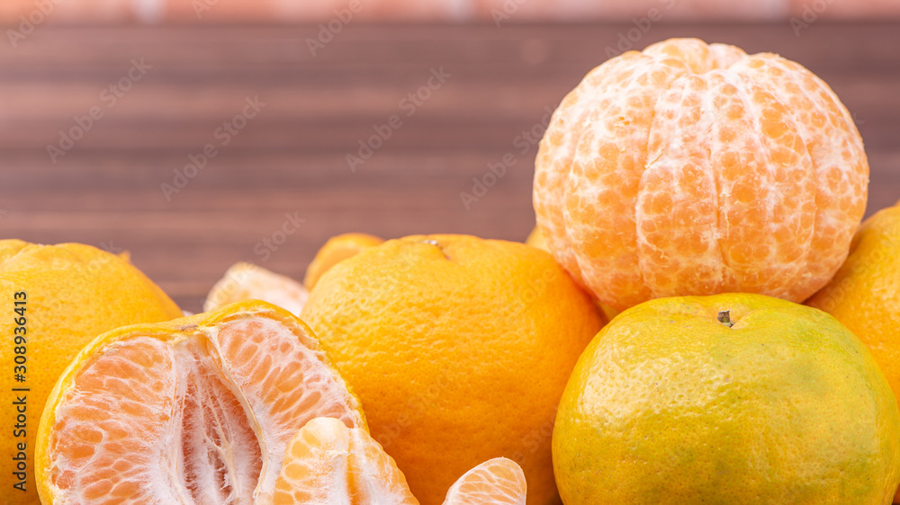 Peeled tangerines in a bamboo sieve basket on dark wooden table with red brick wall background, Chinese lunar new year fruit design concept, close up. Peeled tangerines in a bamboo sieve basket on dark wooden table with red brick wall background, Chinese lunar new year fruit design concept, close up.