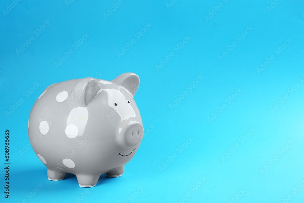 Grey piggy bank on blue background. Space for text