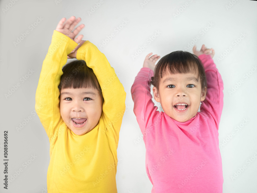 Portrait of a happy smiling brethren girls and hand raised isolated on grey background. Portrait of a happy smiling brethren girls and hand raised isolated on grey background.