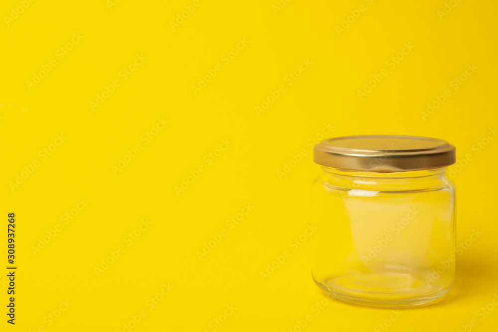 Closed empty glass jar on yellow background, space for text Closed empty glass jar on yellow background, space for text