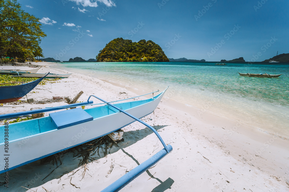 El Nido, Palawan, Philippines. White banca boat at Las cabanas beach with tropical island in background. Beautiful landscape scenery