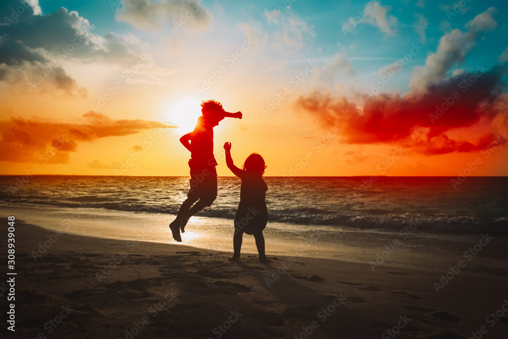 kids have fun, boy and girl jump at sunset beach