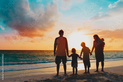 happy family with tree kids walk at sunset beach