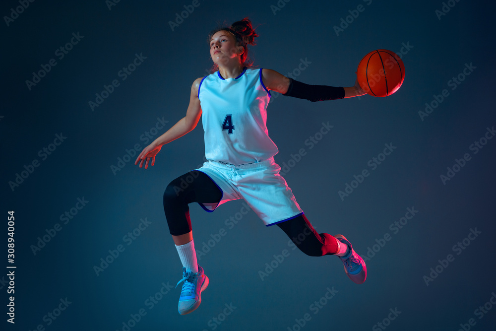 Target. Young caucasian female basketball player on blue studio background in neon light, motion and action. Concept of sport, movement, energy and dynamic, healthy lifestyle. Training, practicing.