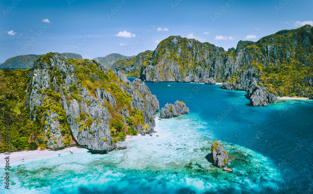 El Nido, Palawan, Philippines. Aerial view of tropical Island with tourist boats moored at white sandy beach. Jugged karst limestone sea stack mountain cliffs. Bacuit archipelago
