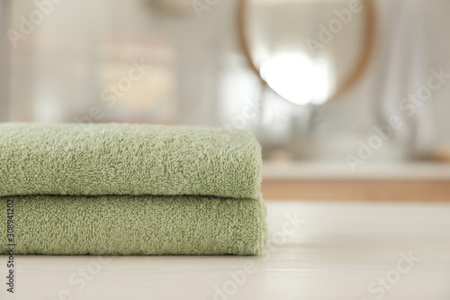 Stack of clean towels on white wooden table in bathroom. Space for text