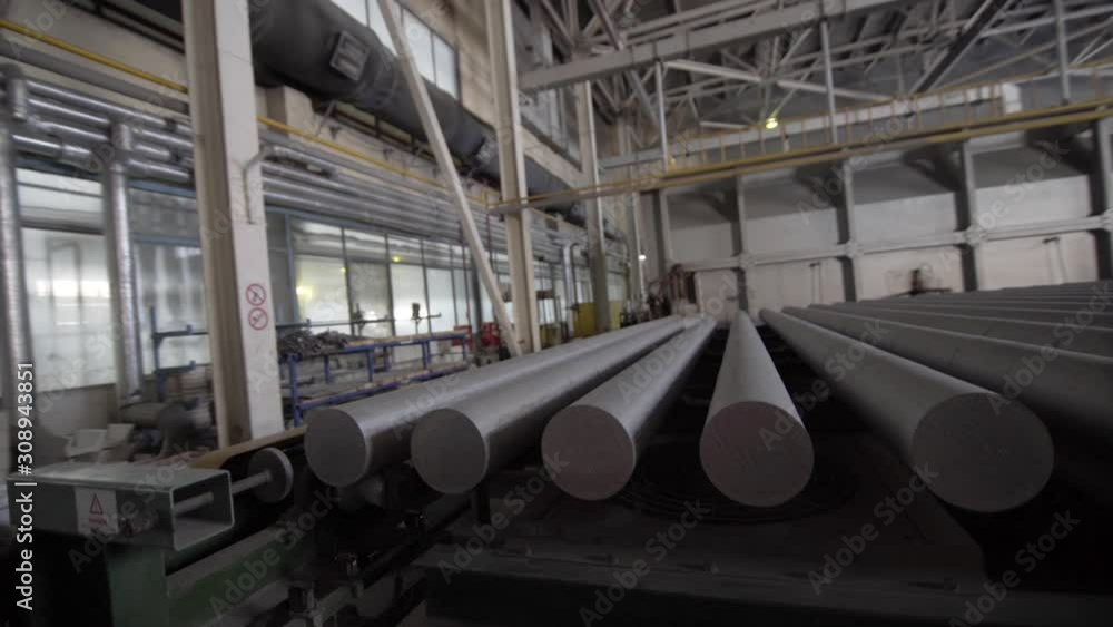 Aluminium extrusion production line in modern factory. Production of Complex lightweight extruded aluminium metal profiles, commonly used as material in construction and manufacturing Aluminium extrusion production line in modern factory. Production of Complex lightweight extruded aluminium metal profiles, commonly used as material in construction and manufacturing