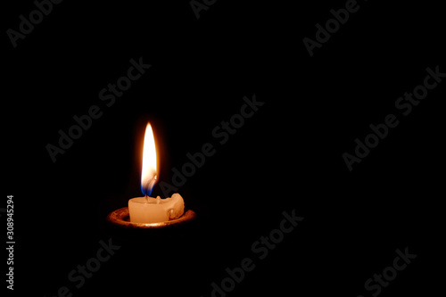 A candle burning in the dark. The candle almost burned out.