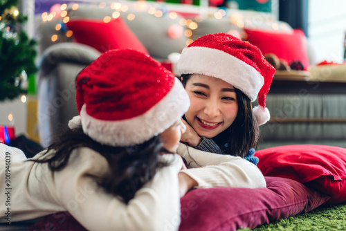 Portrait of happy family mother with daughter in santa hats having fun look at camera and enjoying spending time together in christmas time at home