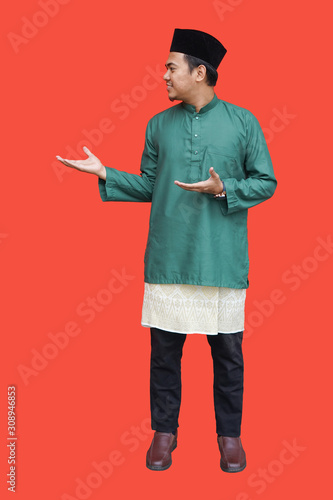 potrait young malay muslim man happy face with green wearing Malaysian traditional cloth baju melayu with samping songket and songkok on red background photo