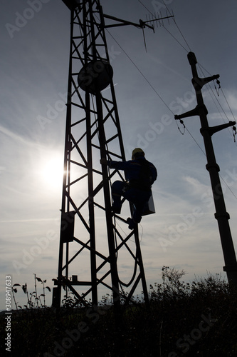 Silhouette of a worker climbing on lamppost © Geza Farkas