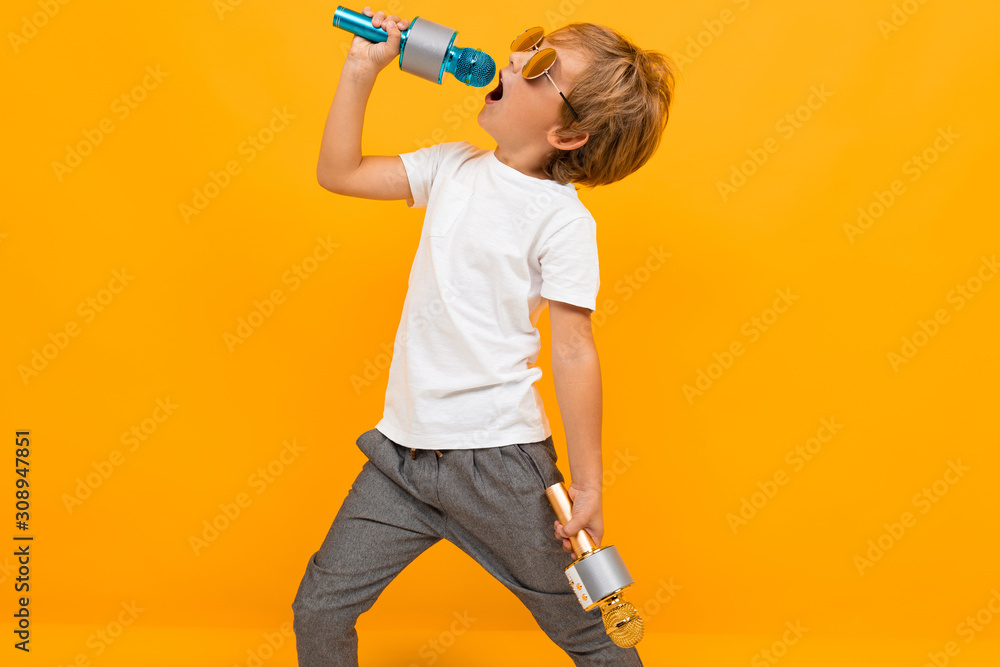 boy enjoys singing into a microphone on an orange background boy enjoys singing into a microphone on an orange background