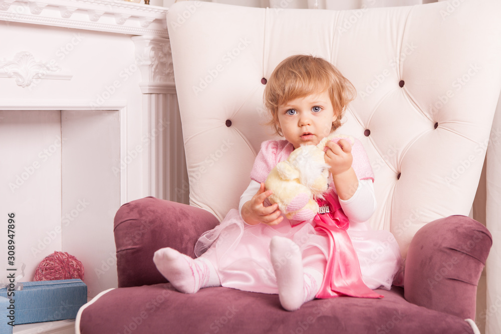 Cute little girl in an elegant dress sits in an armchair Cute little girl in an elegant dress sits in an armchair