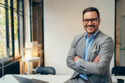 Portrait of young businessman standing in his office with arms crossed photo