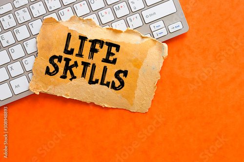 Life skills text on open orange cardboard with keyboard