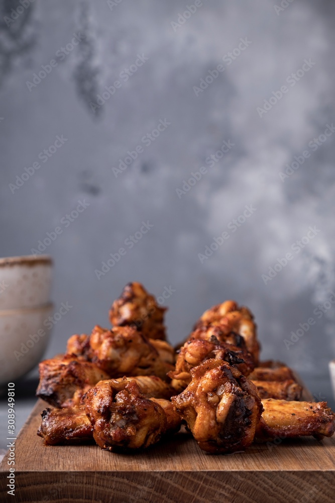 Tasty roasted chicken wings on wooden board with copy space Tasty roasted chicken wings on wooden board with copy space
