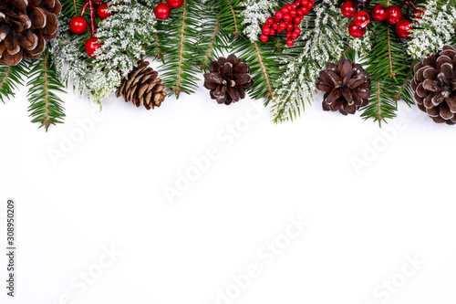 Christmas banner. New Year holidays background. Snowy fir branches, pine cones and red Holly Berries on white background. Christmas and New Year top view decoration with copy space. Part of set.