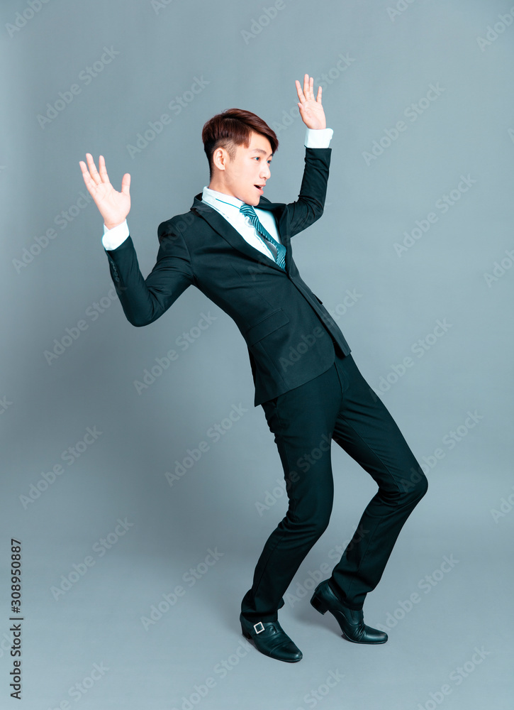 Scared young business man standing before gray background Scared young business man standing before gray background