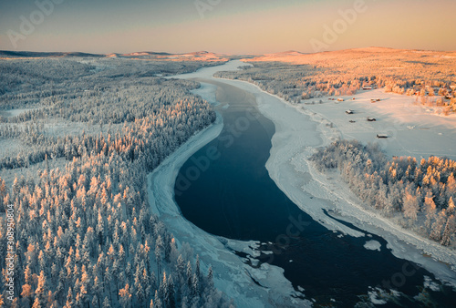 Aerial view of frozen river passing through pine forest photo