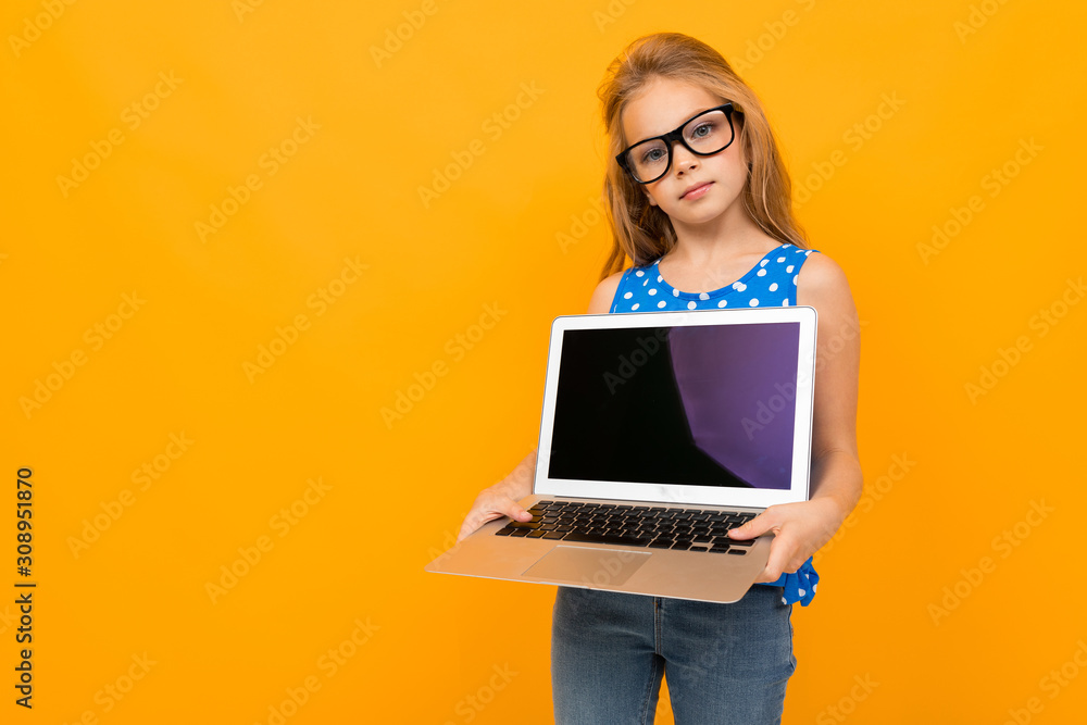 Naklejka premium caucasian girl with a laptop shows a screen with mockup on a yellow background