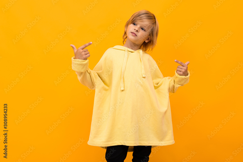 cool blond boy with a panama in a light hoodie with glasses posing on a yellow studio background cool blond boy with a panama in a light hoodie with glasses posing on a yellow studio background