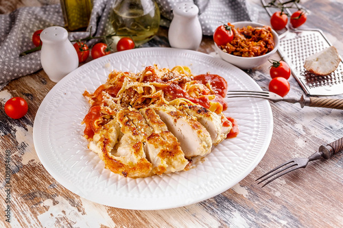 Spaghetti with grilled chicken fillet with tomato sauce on a white plate. Traditional Italian Mediterranean cuisine.